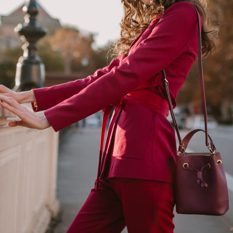 close up fashion details of stylish woman in purple suit walking in city street, spring summer autumn season fashion trend holding purse